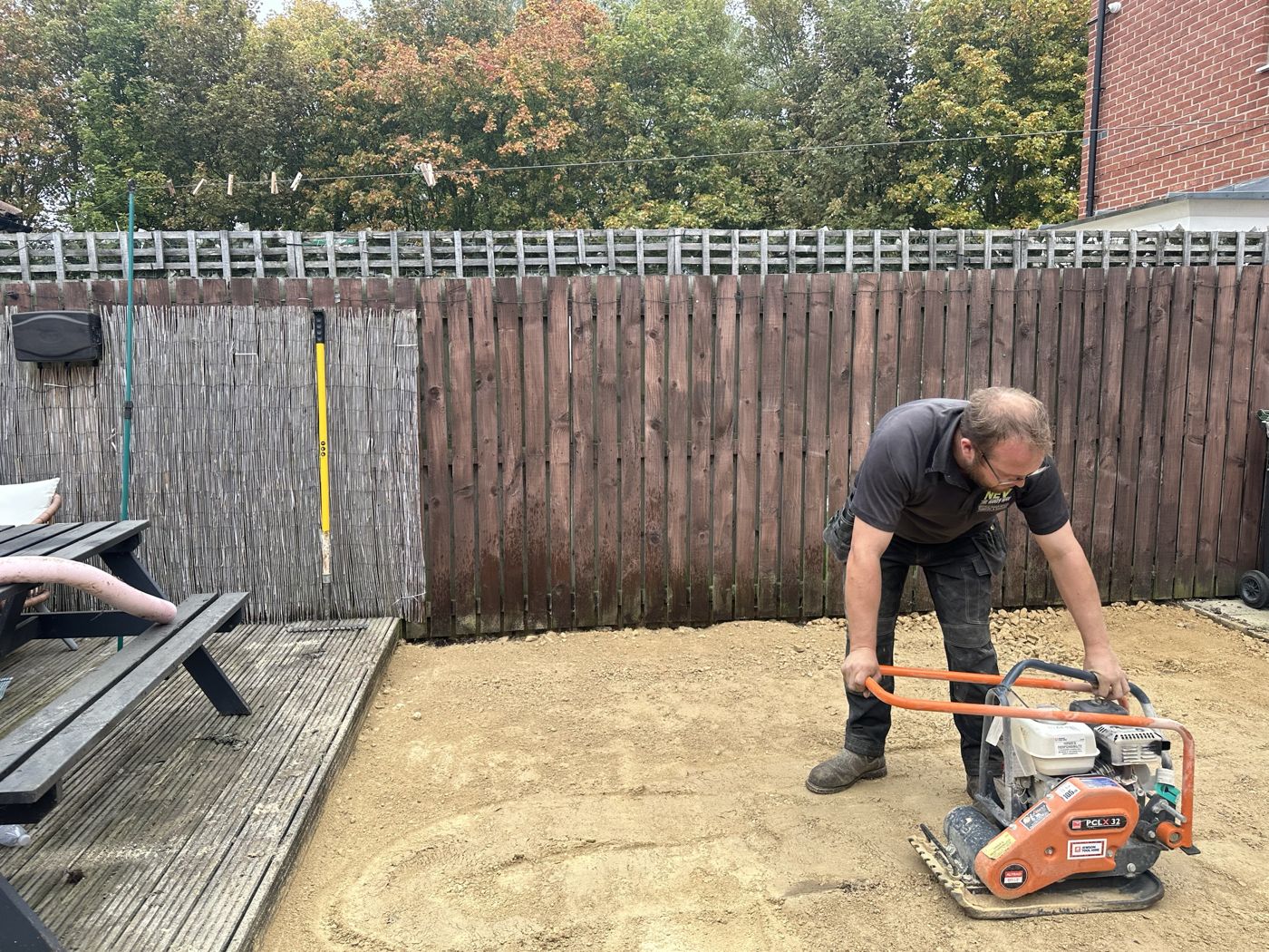 Nev compacting the sub-base next to the decking and fence line