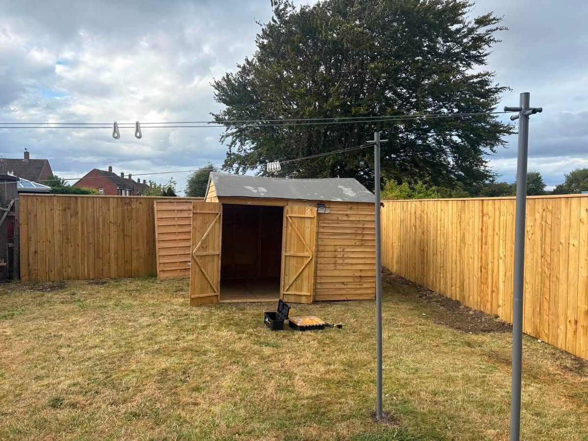 Finished timber shed with doors open against the new fence